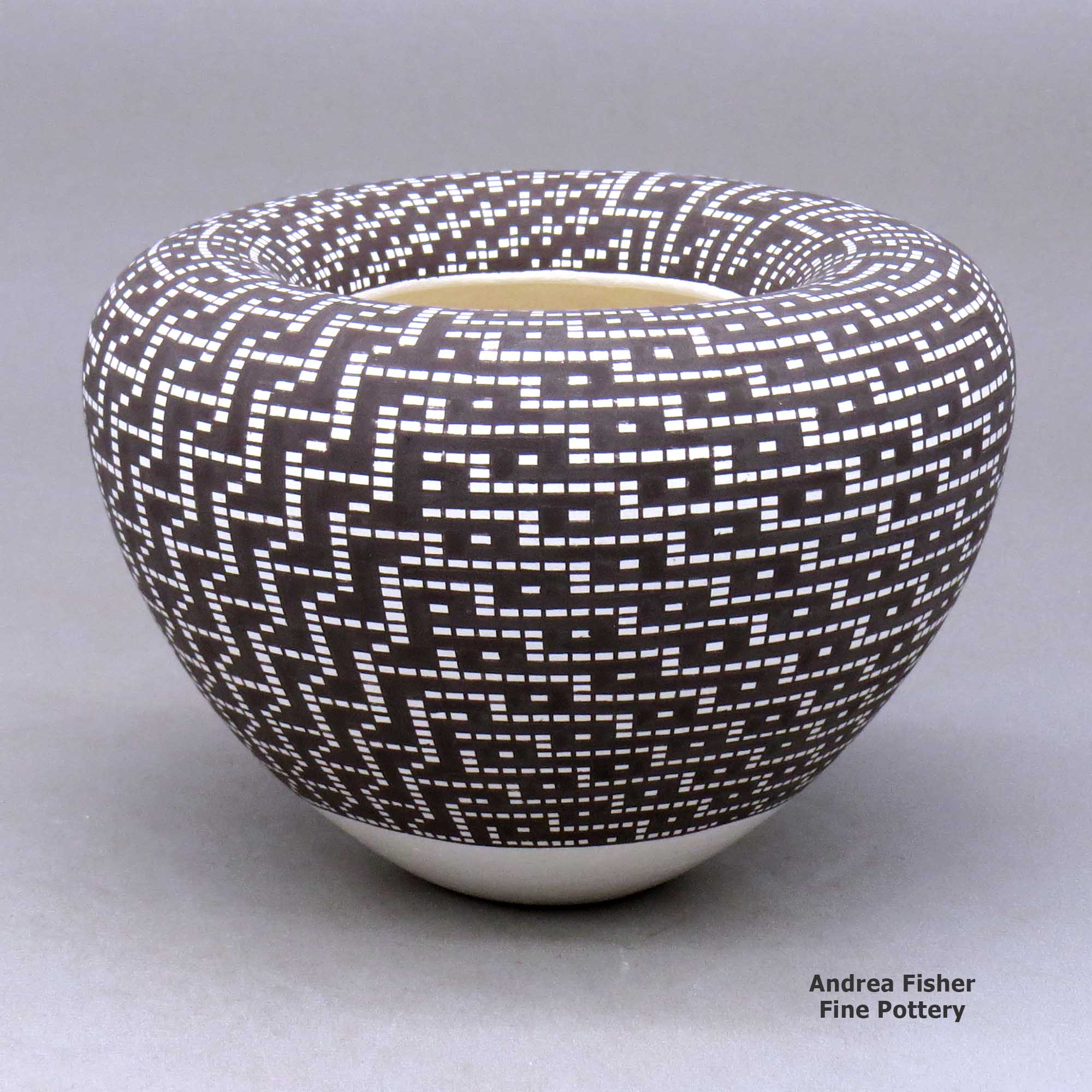 Click or tap to see a larger view A black on white jar with an infinity rim and decorated with a four-panel geometric design built of filling in tiny squares in a grid made by Frederica Antonio of Acoma