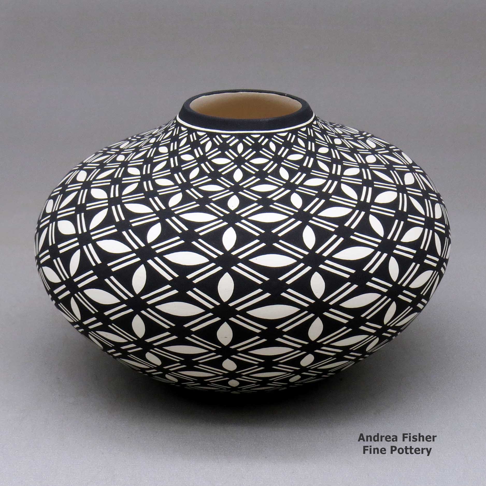 Click or tap to see a larger view A black on white jar decorated with a pumpkin seed snowflake and geometric design made by Paula Estevan of Acoma