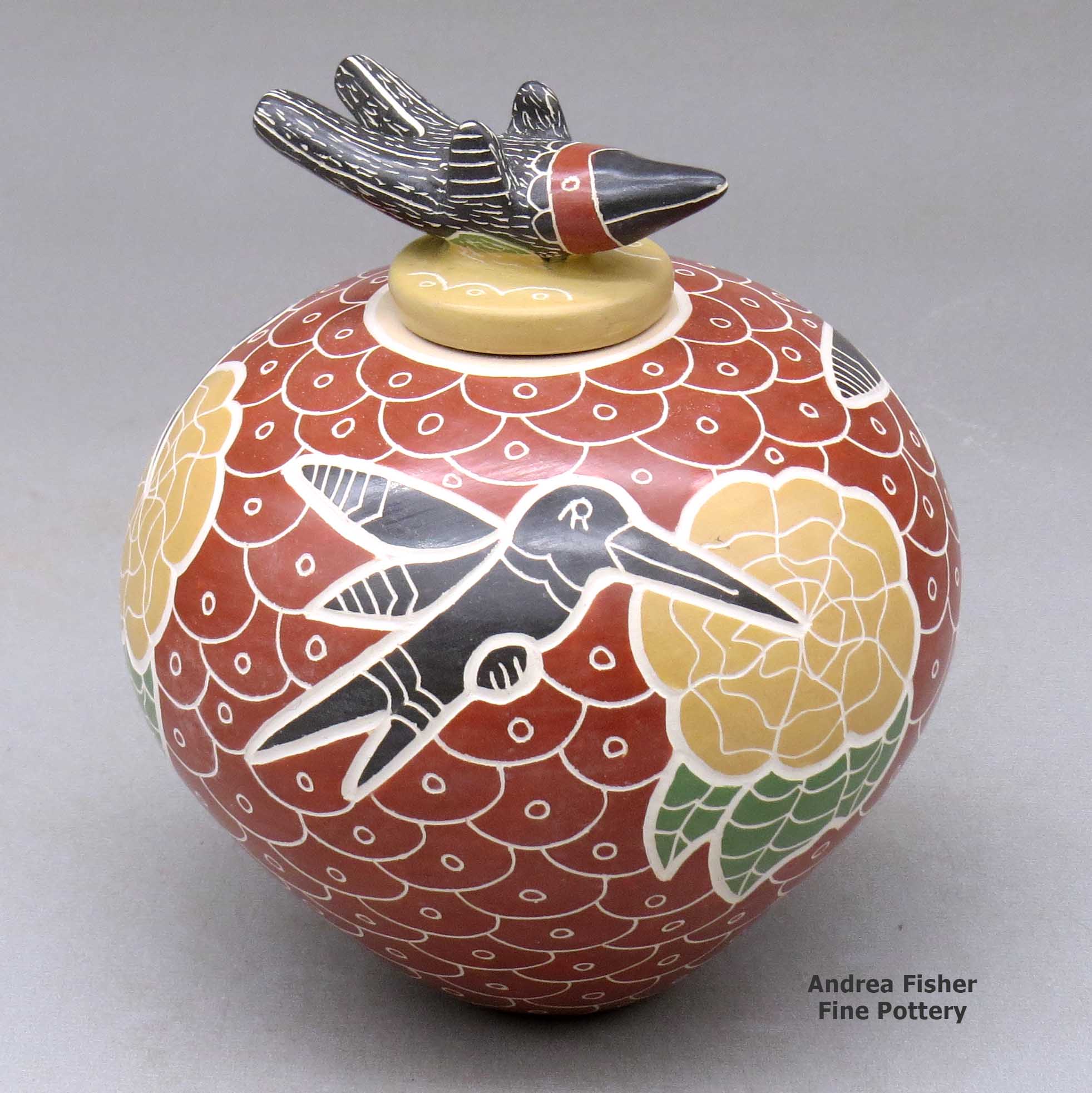 Click or tap to see a larger view A polychrome jar decorated with a lightly-carved, sgraffito and painted hummingbird, flower, and mesh geometric design, plus a matching hummingbird lid made by Vidal Corona of Mata Ortiz and Casas Grandes