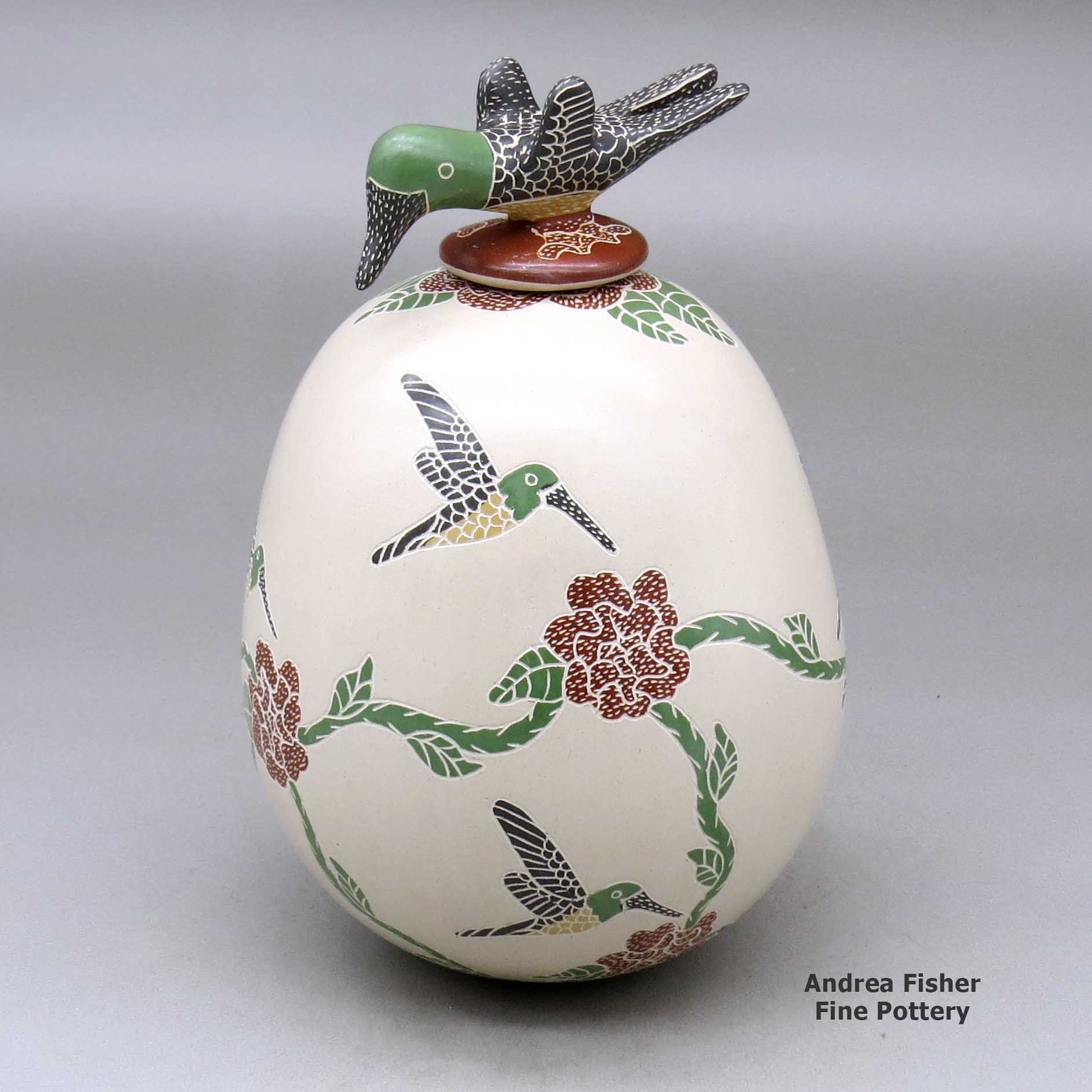 Click or tap to see a larger view A polychrome jar decorated with a sgraffito and painted hummingbird, flower and vine design, plus a hummingbird lid made by Luz Elva Gutierrez of Mata Ortiz and Casas Grandes