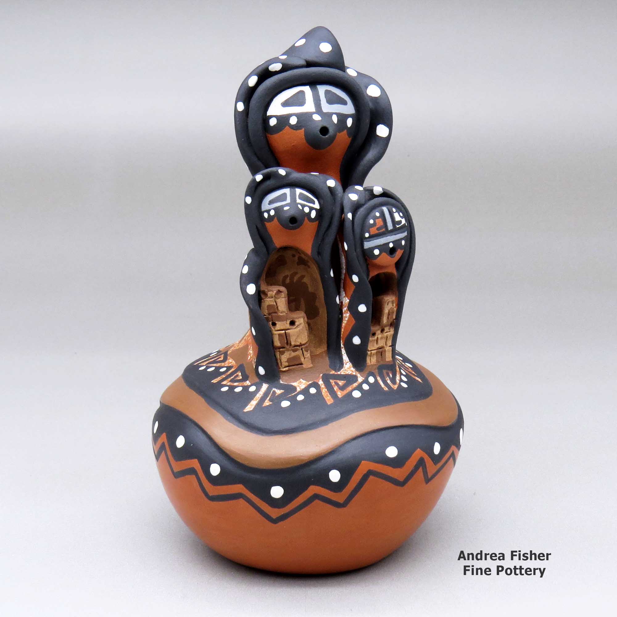 Click or tap to see a larger view A polychrome mudhead storyteller with two children on top of a carved and painted jar made by Felicia Fragua of Jemez