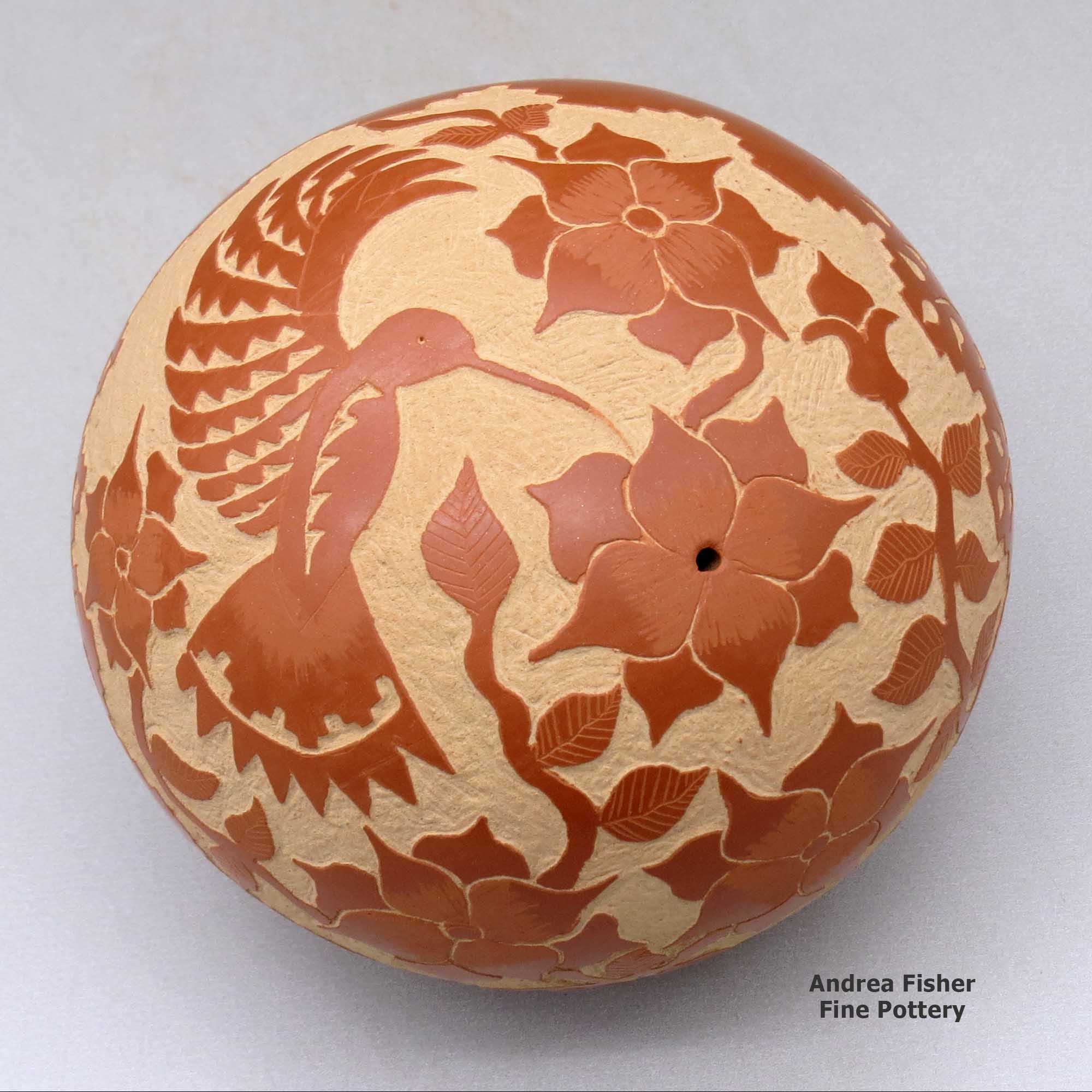 Click or tap to see a larger view A red seed pot decorated with a sgraffito hummingbird, flower, vine and geometric design made by Alvina Yepa of Jemez