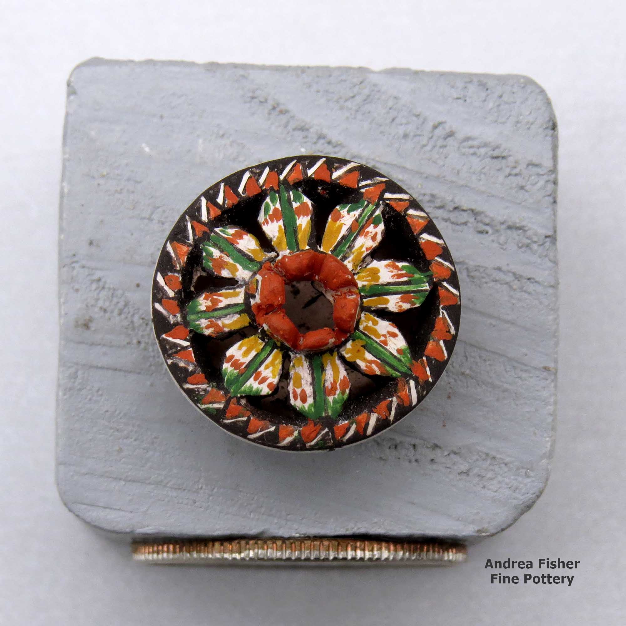 Click or tap to see a larger view A miniature polychrome flat-topped jar decorated with a notched rim, cutouts and a flower and geometric design made by Thomas Natseway of Laguna