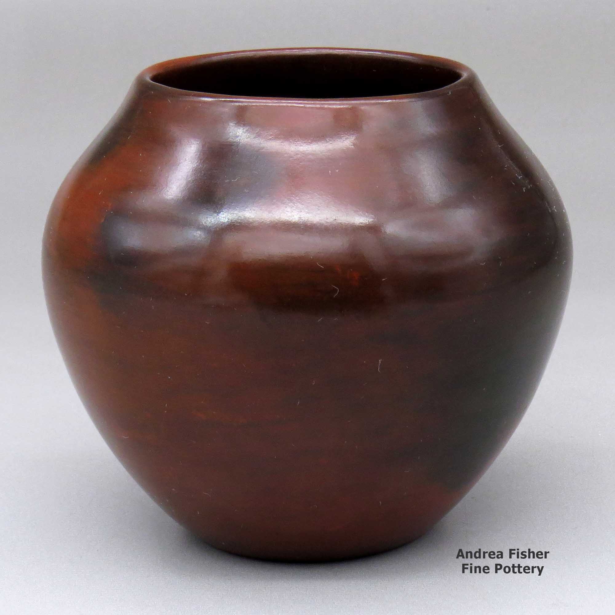 Click or tap to see a larger view A polished brown jar decorated with fire clouds made by Susie Crank of Dineh