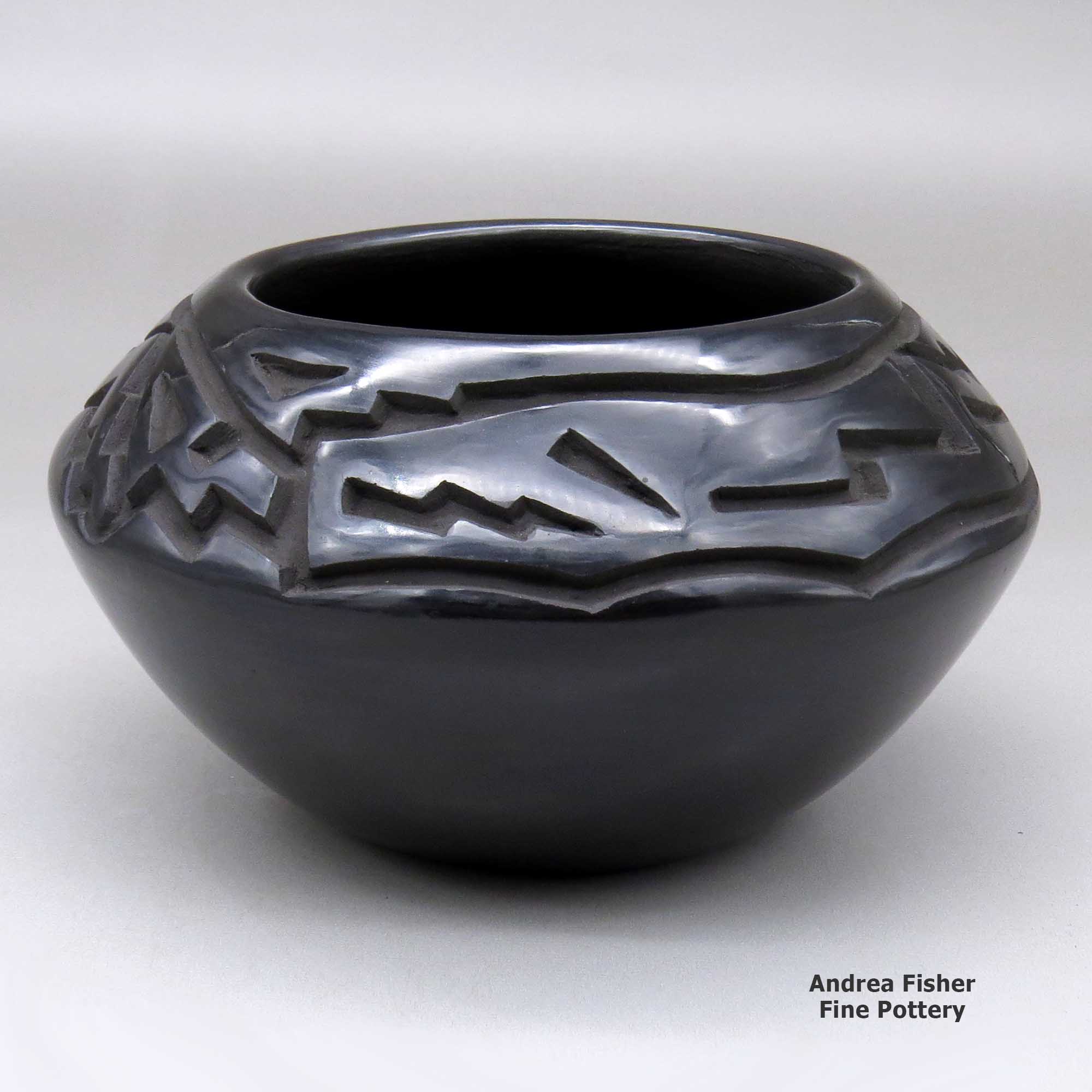 Click or tap to see a larger view A black bowl carved above the shoulder with an avanyu and geometric design made by Chris Martinez of Santa Clara