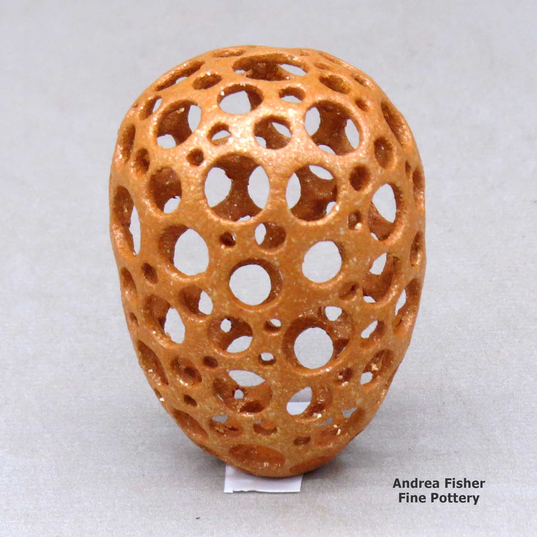 Click or tap to see a larger view A miniature golden micaceous holey pot made by Hubert Candelario of San Felipe