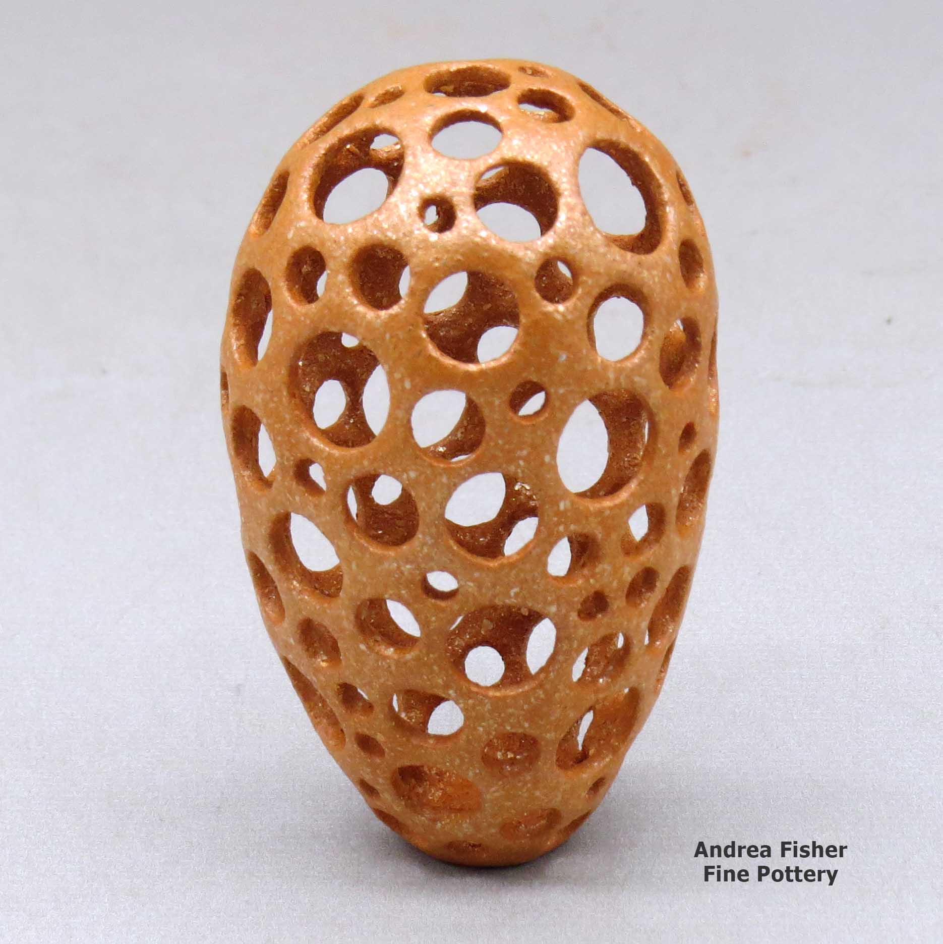 Click or tap to see a larger view A small golden micaceous holey pot made by Hubert Candelario of San Felipe