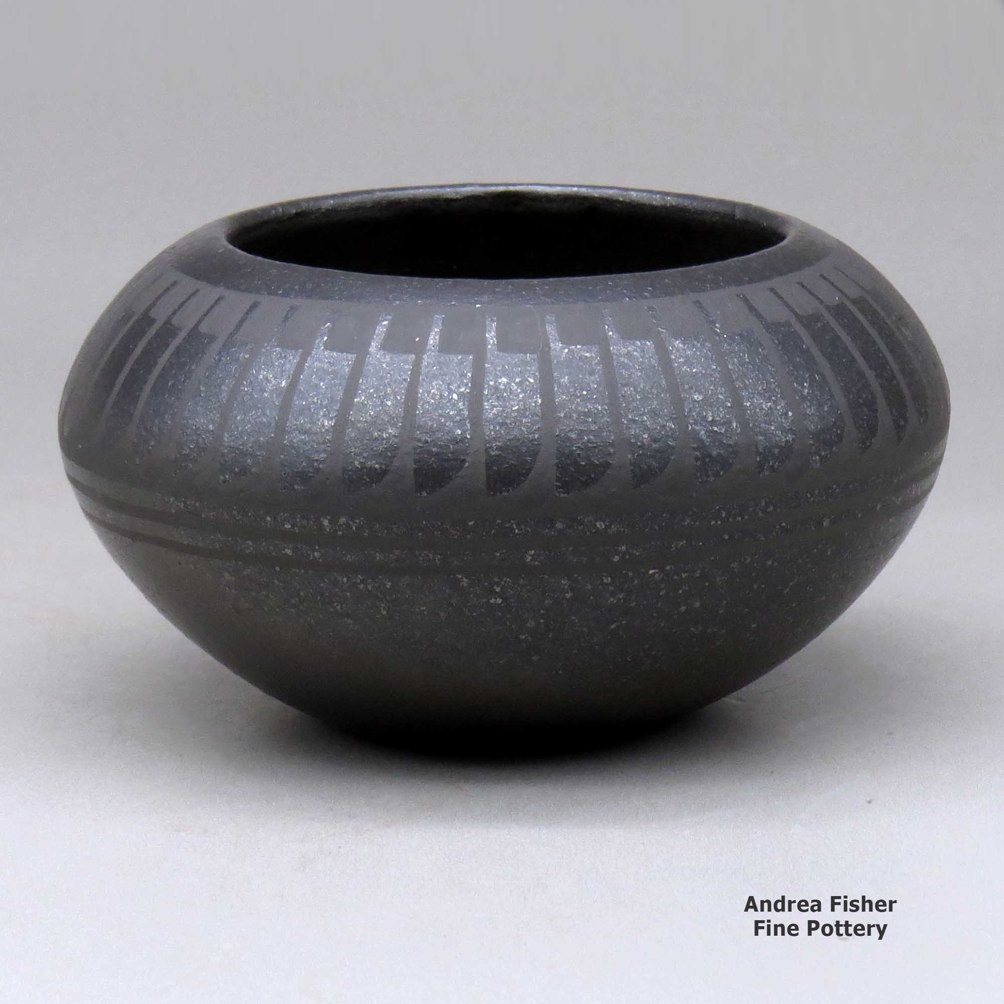 Click or tap to see a larger view A black on micaceous black bowl decorated with a band of feathers above the shoulder made by Johnny Cruz of San Ildefonso