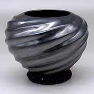 A glossy black melon bowl with eight spiraling repousse ribs
 by Paty Rodriguez of Mata Ortiz and Casas Grandes