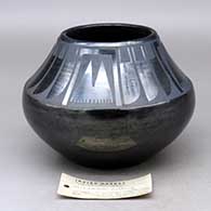 A black on black jar decorated with a four-panel feather and geometric design above the shoulder, Tag indicates it was first sold at the 1939 Golden Gate International Exposition
 by Maria Martinez of San Ildefonso