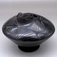 A black on black jar decorated with a geometric design and a sculpted bighorn ram head on the rim
 by Jose Quezada of Mata Ortiz and Casas Grandes