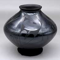 A black on black jar with a flared lip and decorated around the body with a four panel geometric design
 by Rito Talavera of Mata Ortiz and Casas Grandes