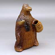 A small brown bear figure holding a honey pot and decorated with fire clouds
 by Louise Goodman of Dineh