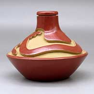 A low shouldered red jar with a thin neck and carved above the shoulder with an avanyu design, click or tap to see a larger version