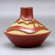 A low shouldered red jar with a thin neck and carved above the shoulder with an avanyu design, click or tap to see a larger version