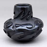 A small low shouldered black jar carved with an avanyu and geometric design
 by Victor and Naomi Eckleberry of Santa Clara