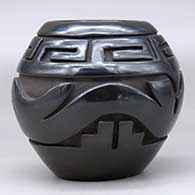 A black jar carved around the body with an avanyu  and scrolls design, click or tap to see a larger version