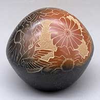 A black seed pot with a large sienna spot and decorated with a sgraffito hummingbird, flower, leaf, vine and geometric design
 by Eric Tafoya of Santa Clara