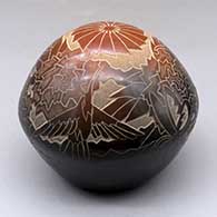 A black seed pot with a large sienna spot and decorated with a sgraffito hummingbird, flower, leaf, vine and geometric design
 by Eric Tafoya of Santa Clara