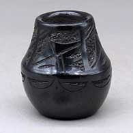 A small black jar decorated with a four panel sgraffito geometric design with micaceous highlights
 by Rose Lovato-Fragua of San Ildefonso
