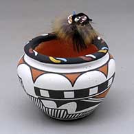 A polychrome jar decorated with a two panel geometric design around the body and a kolowisi pattern around the rim with an applique kolowisi head and dressing
 by Marcus Homer of Zuni