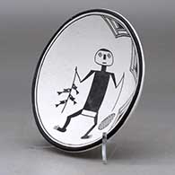 A shallow black on white bowl decorated with a fisherman, fish and geometric design, click or tap to see a larger version