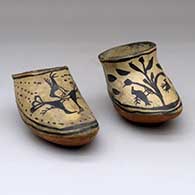 A pair of polychrome ceramic slippers decorated with bird, plant, footprint and geometric designs
 by Unknown of Cochiti