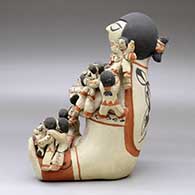 A polychrome sitting grandfather storyteller figure holding sixteen children with puppies, a drum and a ball, click or tap to see a larger version