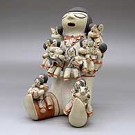 A polychrome sitting grandfather storyteller figure holding sixteen children with puppies, a drum and a ball, click or tap to see a larger version