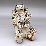 A polychrome sitting grandfather storyteller figure holding sixteen children with puppies, a drum and a ball
 by Dorothy Trujillo of Cochiti