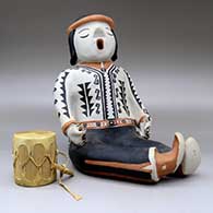 A sitting singing drummer figure decorated with a geometric design and holding a drum, click or tap to see a larger version