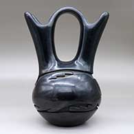 A black wedding vase carved around the body with an avanyu design, click or tap to see a larger version