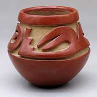 A red jar carved above the shoulder with a stylized avanyu design
 by Teresita Naranjo of Santa Clara