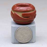 A miniature red bowl carved on the outside with a stylized avanyu design
 by Teresita Naranjo of Santa Clara