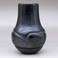 A black jar with a tall neck and carved around the shoulder with a geometric design, click or tap to see a larger version