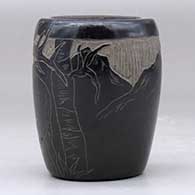 A small black jar decorated with a sgraffito elk and nature design, click or tap to see a larger version