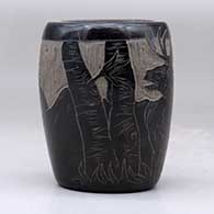 A small black jar decorated with a sgraffito elk and nature design, click or tap to see a larger version