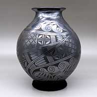 A black on black jar with a rolled lip and a two-panel medallion, bird, spiral and geometric design, click or tap to see a larger version