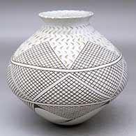 A black-on-white jar with a notched rim and decorated with a five-panel tooled and painted geometric design
 by Dora Quezada of Mata Ortiz and Casas Grandes