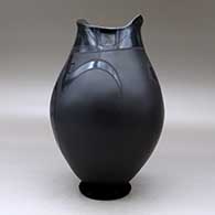 A black on black on black jar with a geometric cut opening and decorated with a a two panel geometric design, click or tap to see a larger version