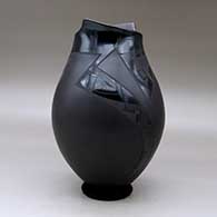 A black on black on black jar with a geometric cut opening and decorated with a a two panel geometric design, click or tap to see a larger version