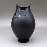 A black on black on black jar with a geometric cut opening and decorated with a a two panel geometric design, click or tap to see a larger version