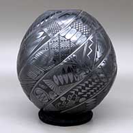 A black on black spiraled repousse melon jar with eight ribs decorated with fish, birds, rabbits and geometric design on the ribs, click or tap to see a larger version