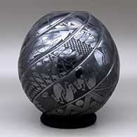 A black on black spiraled repousse melon jar with eight ribs decorated with fish, birds, rabbits and geometric design on the ribs, click or tap to see a larger version