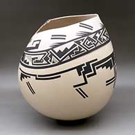 A large black on beige jar with a kiva step cut organic opening and a lightly carved and painted serpent, fish and geometric design, click or tap to see a larger version