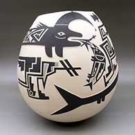 A large black on beige jar with a kiva step cut organic opening and a lightly carved and painted serpent, fish and geometric design, click or tap to see a larger version