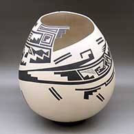 A large black on beige jar with a kiva step cut organic opening and a lightly carved and painted serpent, fish and geometric design
 by Martin Cota of Mata Ortiz and Casas Grandes