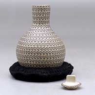 A small tall necked lidded jar decorated with a tiny lines geometric design, click or tap to see a larger version