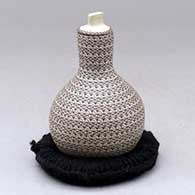 A small tall necked lidded jar decorated with a tiny lines geometric design
 by Karla Lopez Cota of Mata Ortiz and Casas Grandes
