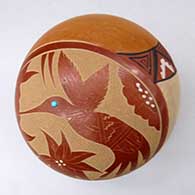 A polychrome seed pot decorated with a sgraffito and painted hummingbird, flower and geometric design, plus an inlaid stone
 by Helen Tafoya of Jemez